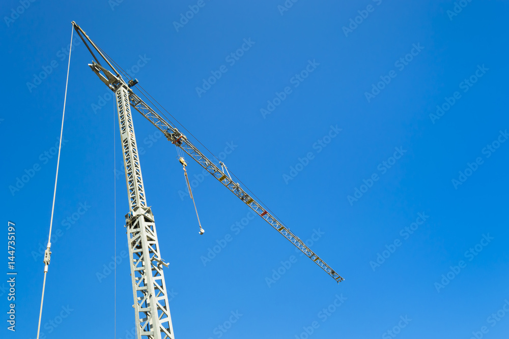 Crane at the construction site. Against the background of a blue clear sky.