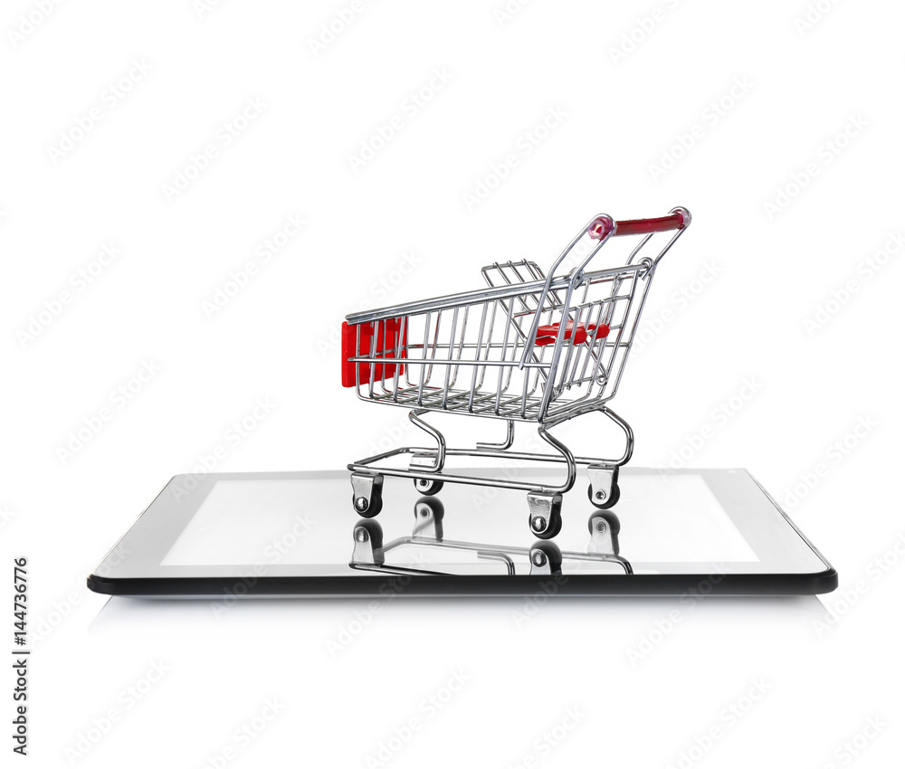 Online shopping concept. Tablet with mini market trolley on white background