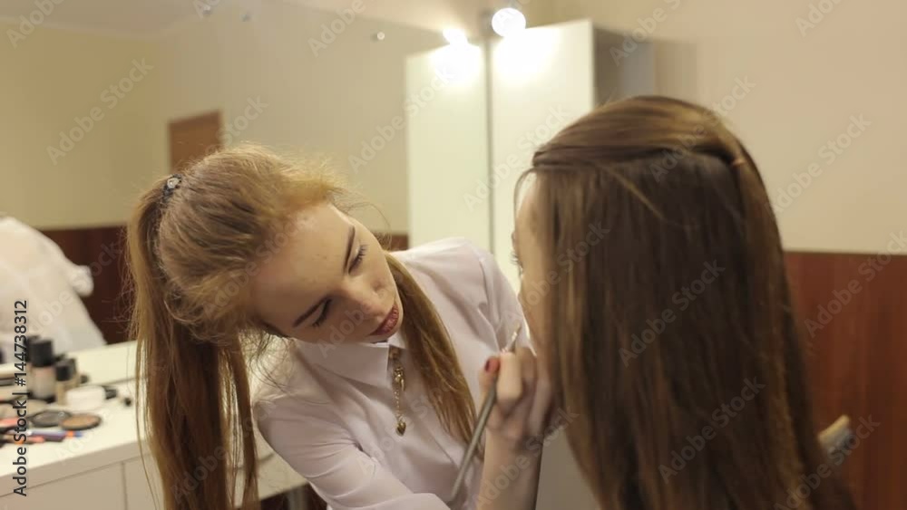 Professional make-up artist doing make-up to a young beautiful brunette girl, close-up. Professional make-up artist doing make-up to a young beautiful brunette girl, close-up.
