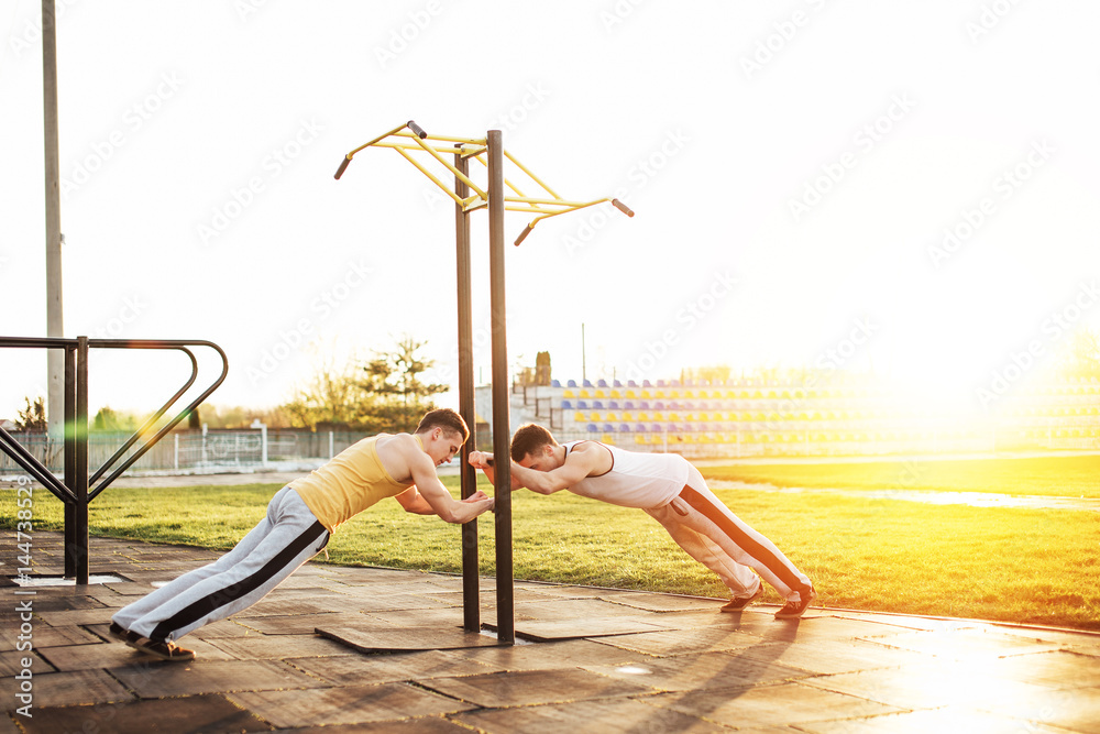 Fototapeta premium Two man stand at stadium with sunset background