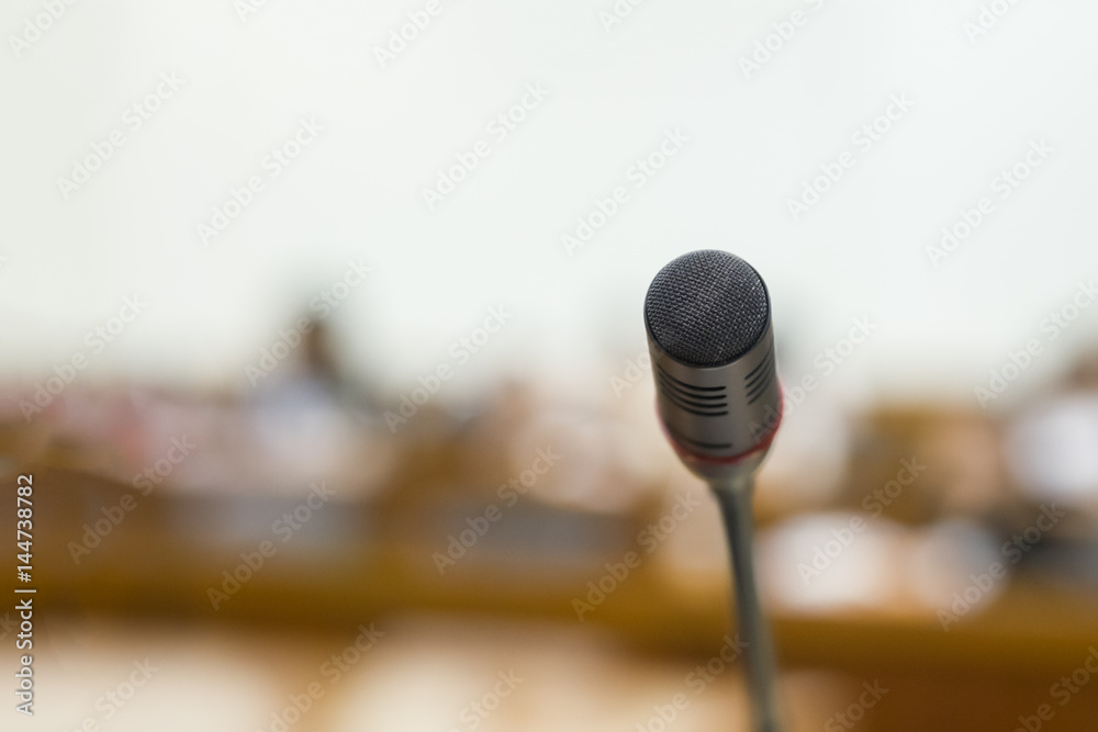 Microphone over the Abstract blurred photo of conference hall or seminar room background Microphone over the Abstract blurred photo of conference hall or seminar room background