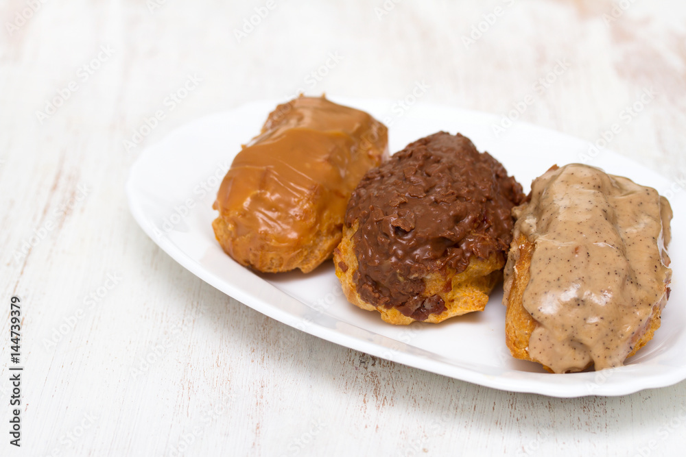 choclate eclairs on white dish on wooden background choclate eclairs on white dish on wooden background