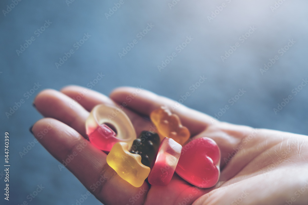 Colorful Jellys on woman's hands with gray color background