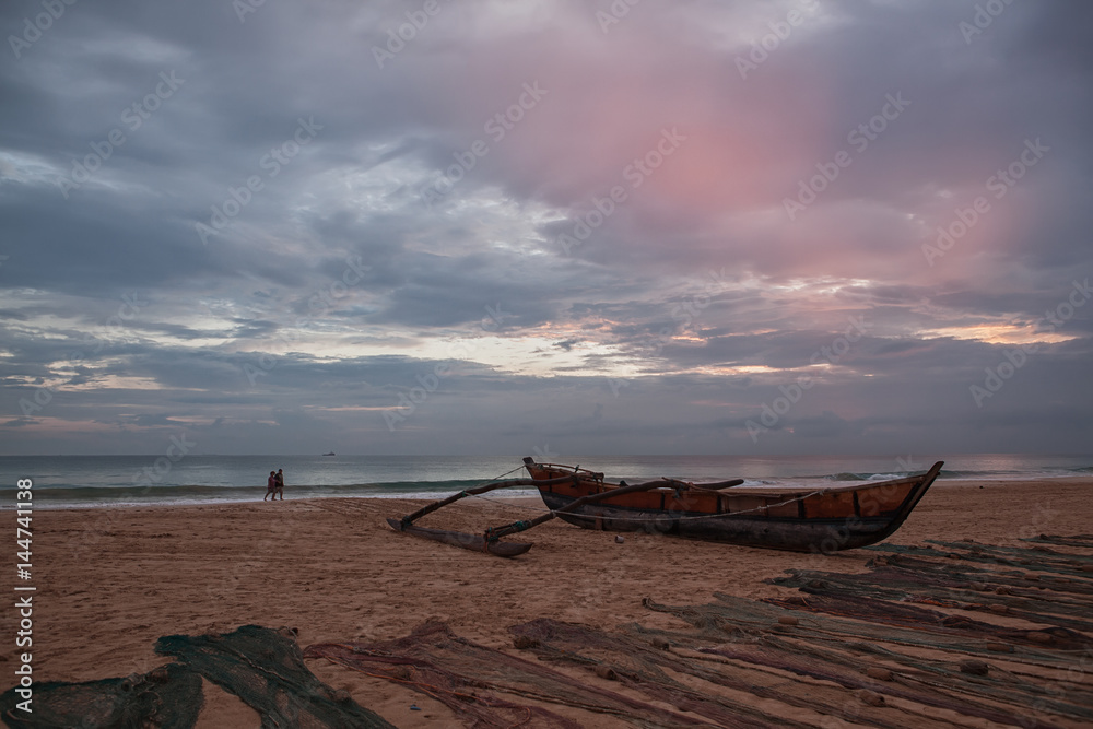Традиционная рыбацкая лодка и сети на берегу.