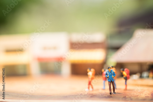 Miniature people with traveling concepts. Group of backpackers walking by the travel attraction spot and shops. Concept of traveling or exploring the world, budget travel