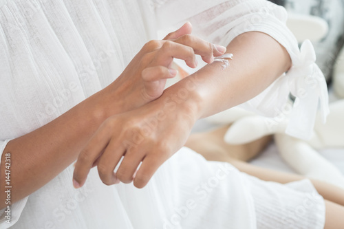 Closeup of female hands applying cream on her arm. Make up, healthy skin, beauty shot, cute asian woman concept
