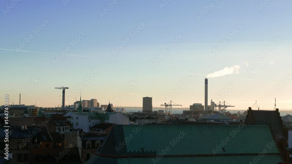View of industrial district in Helsingborg city at dusk. Smokestack, tower crane and harbor area. Cityscape, Sweden View of industrial district in Helsingborg city at dusk. Smokestack, tower crane and harbor area. Cityscape, Sweden