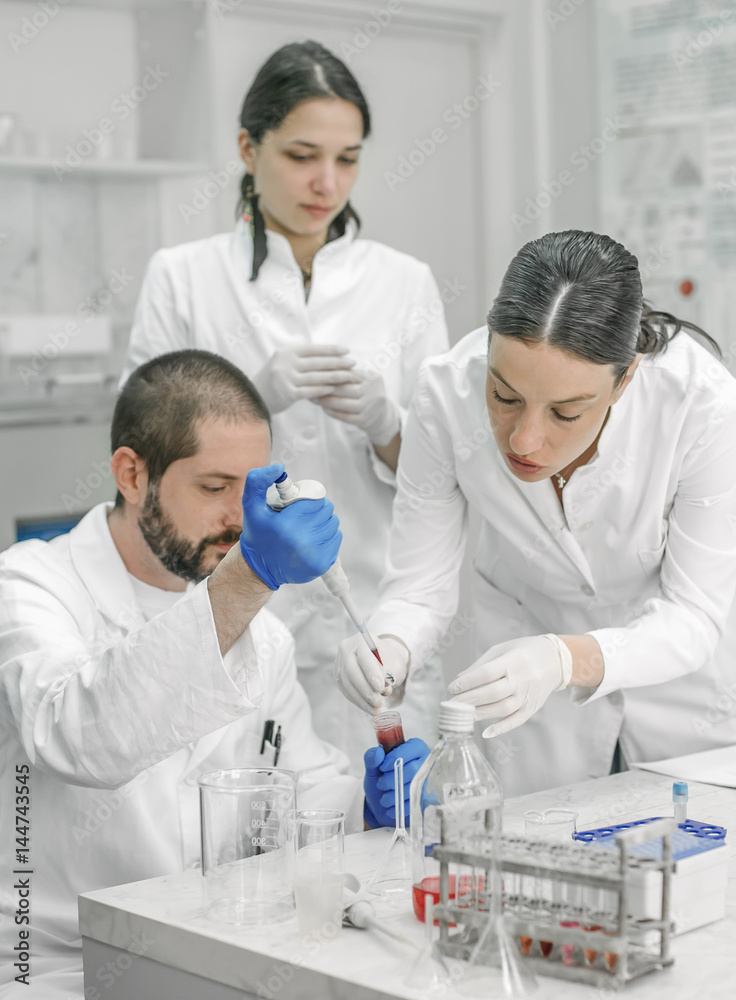 Group of scientists working with liquid test tube samples Group of scientists working with liquid test tube samples