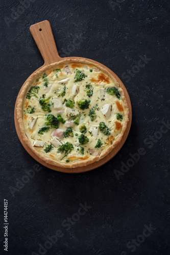 Vegetable pie ( quiche) with broccoli and soft cheese over black  background