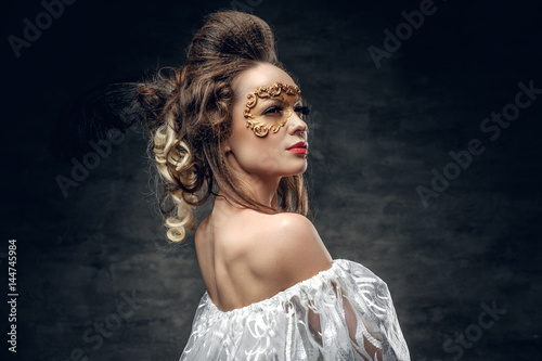 Portrait of brunette female with Carnaval golden mask on her face.