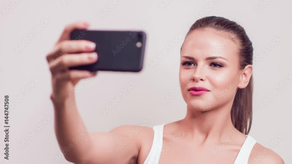 Beautiful girl with a light make-up makes selfie on a white background Beautiful girl with a light make-up makes selfie on a white background