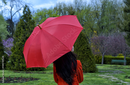 Woman with red umbrella walking in the park 