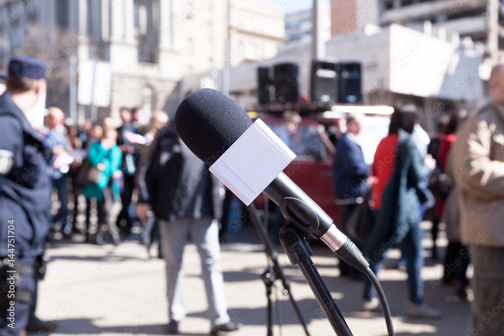 Fototapeta premium Protest. Demonstration. Microphone in focus, blurred protesters in background.