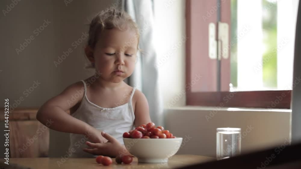 Portrait of cute baby girl eating red cherry tomato Portrait of cute baby girl eating red cherry tomato