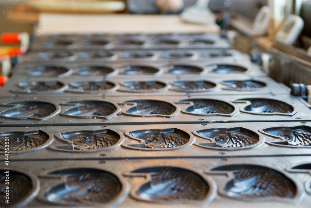 Obraz premium Multiple empty Taiyaki molds on a stove at a shop. Kyushu, Japan. Travel and cuisine concept.