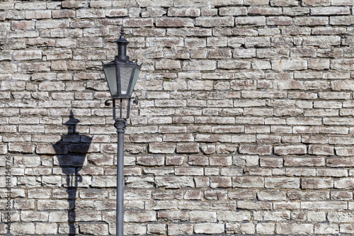 Retro rustic lamppost with lantern on it in front of old stone ancient wall in Old Tallinn, Estonia photo