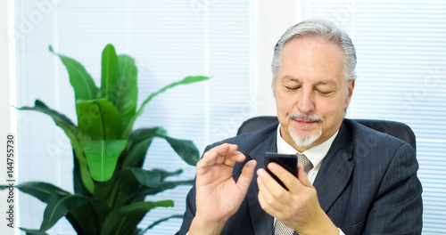 Happy businessman typing on his phone