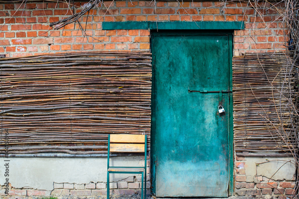 Turquoise door with wooden branches and a chair from natural wood picturesque background Turquoise door with wooden branches and a chair from natural wood picturesque background