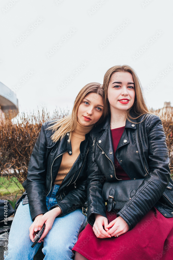Two young girl friends sitting together and having fun Outdoors. lifestyle.