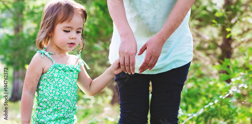 Toddler girl holding hands with her mother