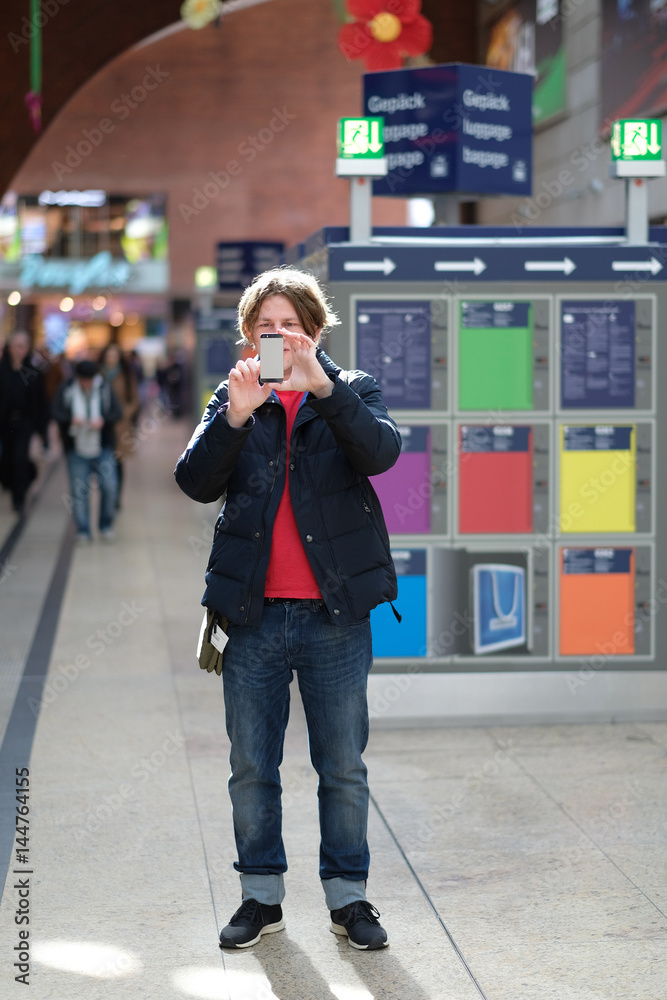 Fototapeta premium A young man with a smartphone in the interior of a shopping center