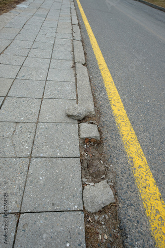 Straße und Gehweg mit zerbrochenen Randstein