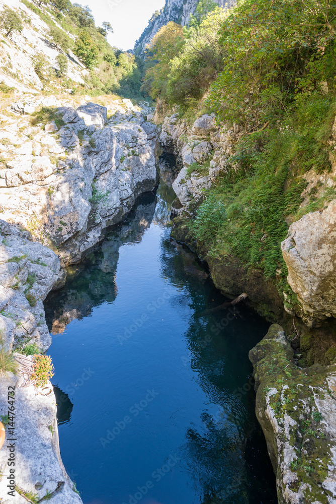 The Rio Cares mountain stream flows through a valley in the foothills of the Picos de Europa National Park. The foothills are also a popular hiking destination and lead along the Camino de Santiago. The Rio Cares mountain stream flows through a valley in the foothills of the Picos de Europa National Park. The foothills are also a popular hiking destination and lead along the Camino de Santiago.