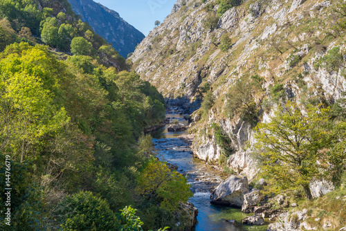 The mountain stream Rio Cares runs through the valley in the foothills of the National Park Picos de Europa. Also the foothills are a popular hiking destination and leads along the Camino de Santiago © ksl