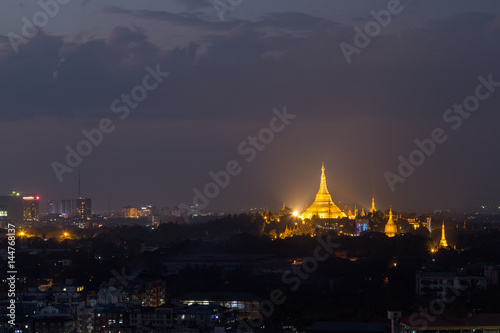 View of lit and golden Shwedagon Pagoda on a hill in Yangon, Myanmar, in the evening. Copy space.