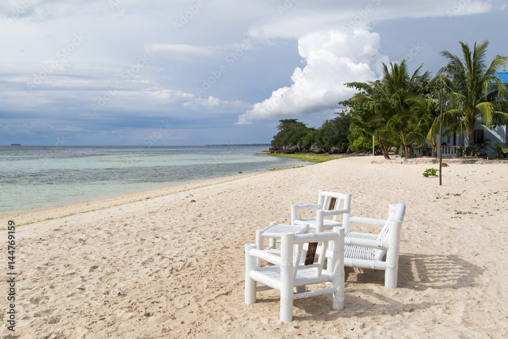 White table and chair on the beach of a sandy beach.