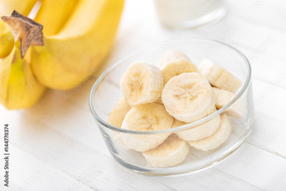 Fresh sliced bananas on white wooden background closeup, healthy eating