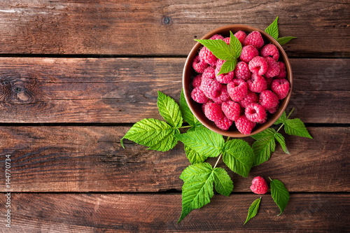 Fotomurale Fresh raspberry with leaves on wooden background