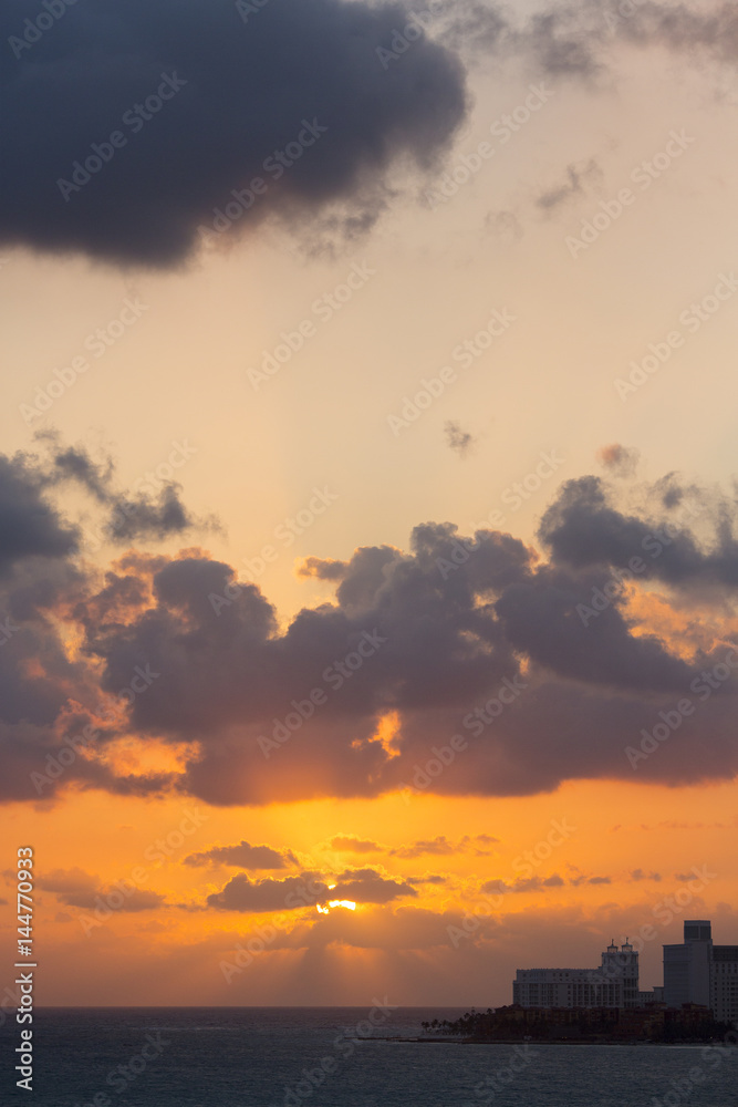 Sunrise behind the island and high buildings. Dramatic sky. Vertical image. Sunrise behind the island and high buildings. Dramatic sky. Vertical image.
