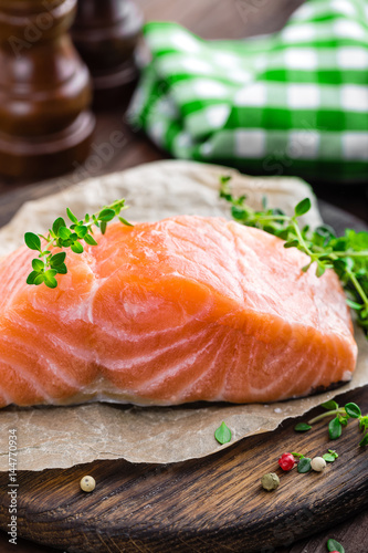 Raw salmon fish fillet on wooden board closeup