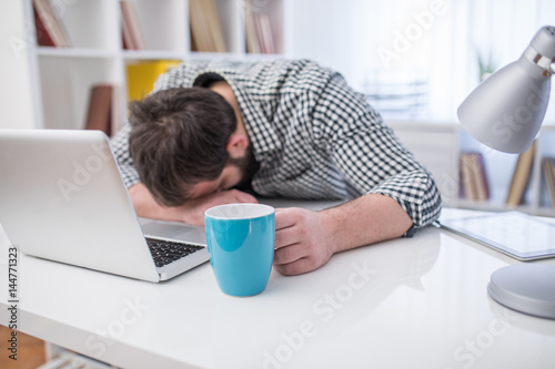 Young business man sleeping on the laptop in office