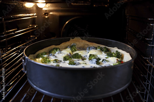 Delicious pie with broccoli on baking tray in oven