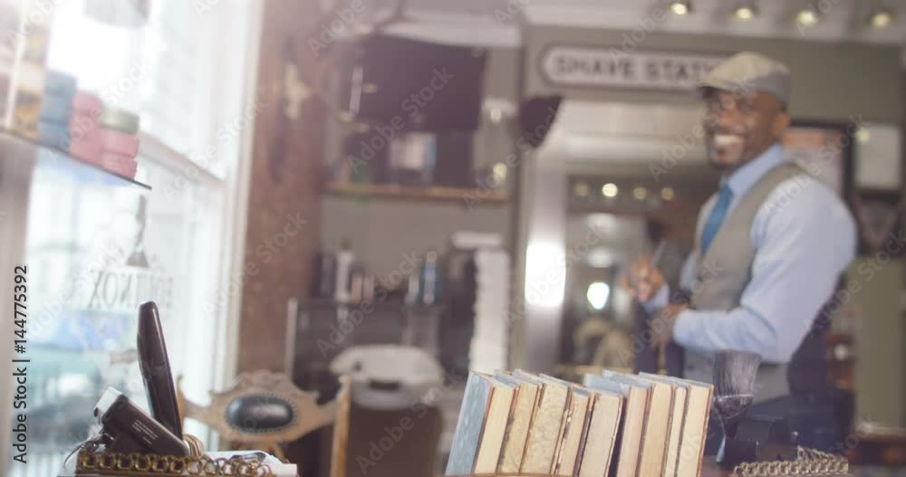  Portrait of smiling barbers behind reception desk in trendy retro barber shop. 