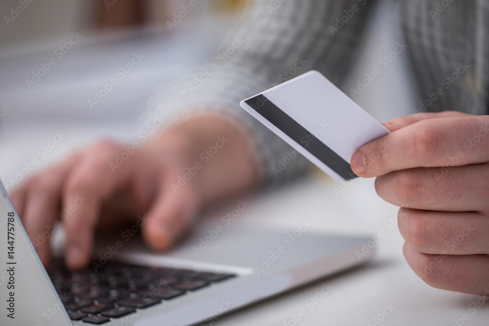 Man holding credit card and using laptop for online shopping in close up
