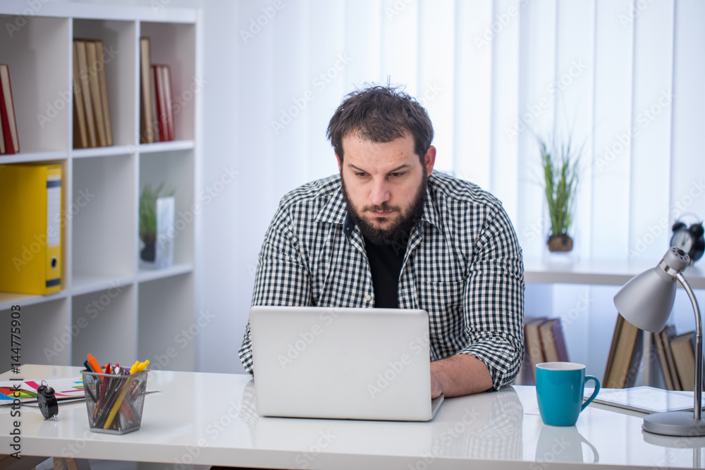 Handsome businessman working with laptop in his office