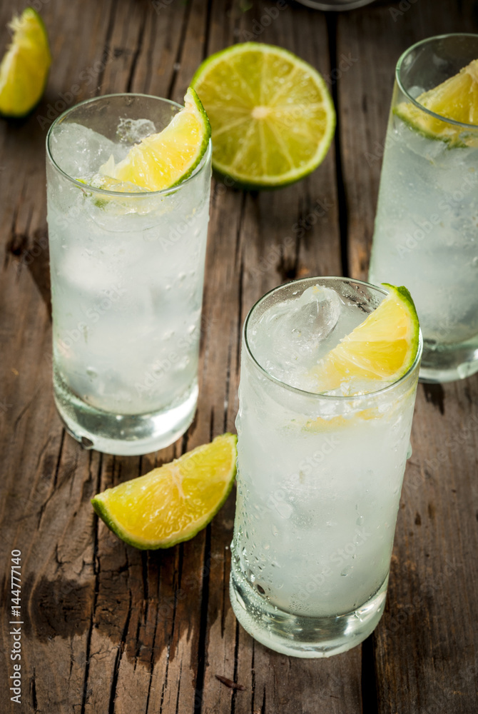 Alcoholic drink. Vodka and tonic highball cocktail with a lime garnish, on an old wooden rustic table. Copy space Alcoholic drink. Vodka and tonic highball cocktail with a lime garnish, on an old wooden rustic table. Copy space