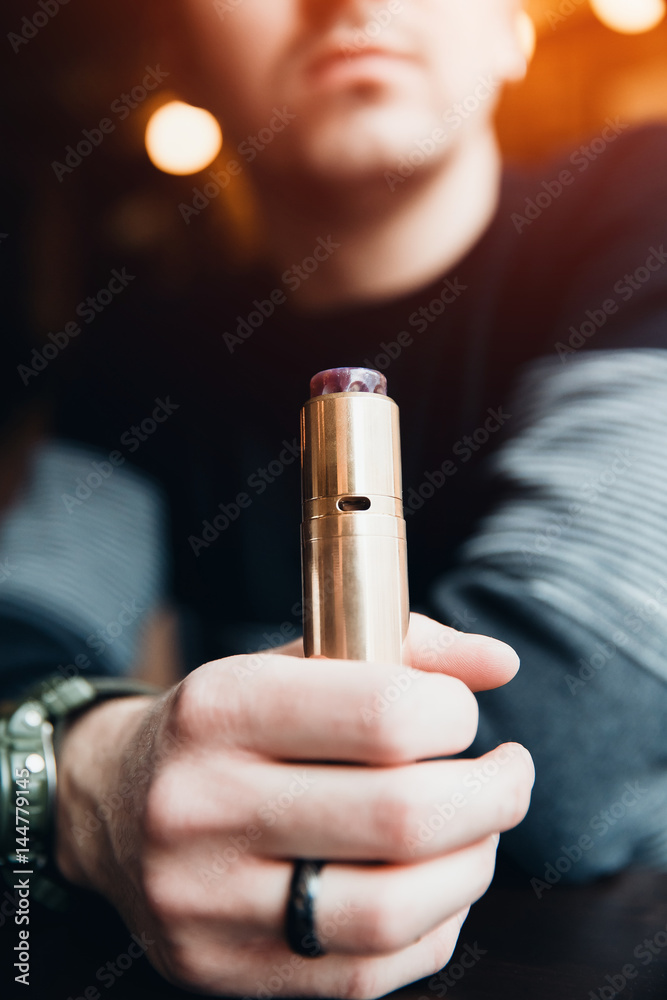 Close-up of electronic cigarette. The man smiles and smokes vape. The concept of refusal of tobacco. Vaping Close-up of electronic cigarette. The man smiles and smokes vape. The concept of refusal of tobacco. Vaping
