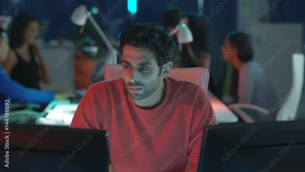 Game designers in young startup company looking at computer screens & sharing ideas. Game designers in young startup company looking at computer screens & sharing ideas.