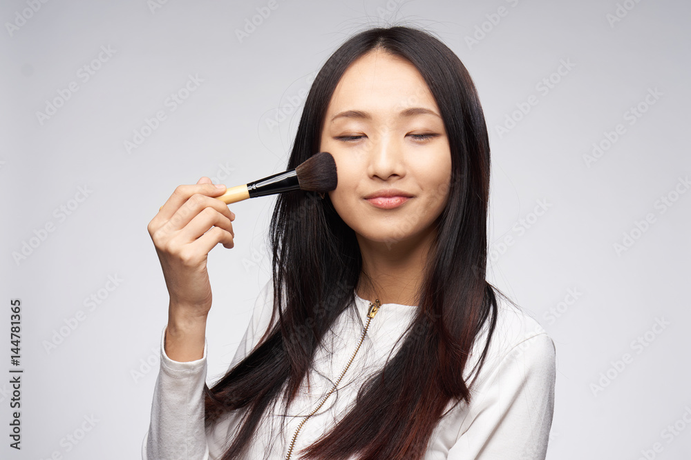 woman with eyes closed applying makeup with a brush woman with eyes closed applying makeup with a brush