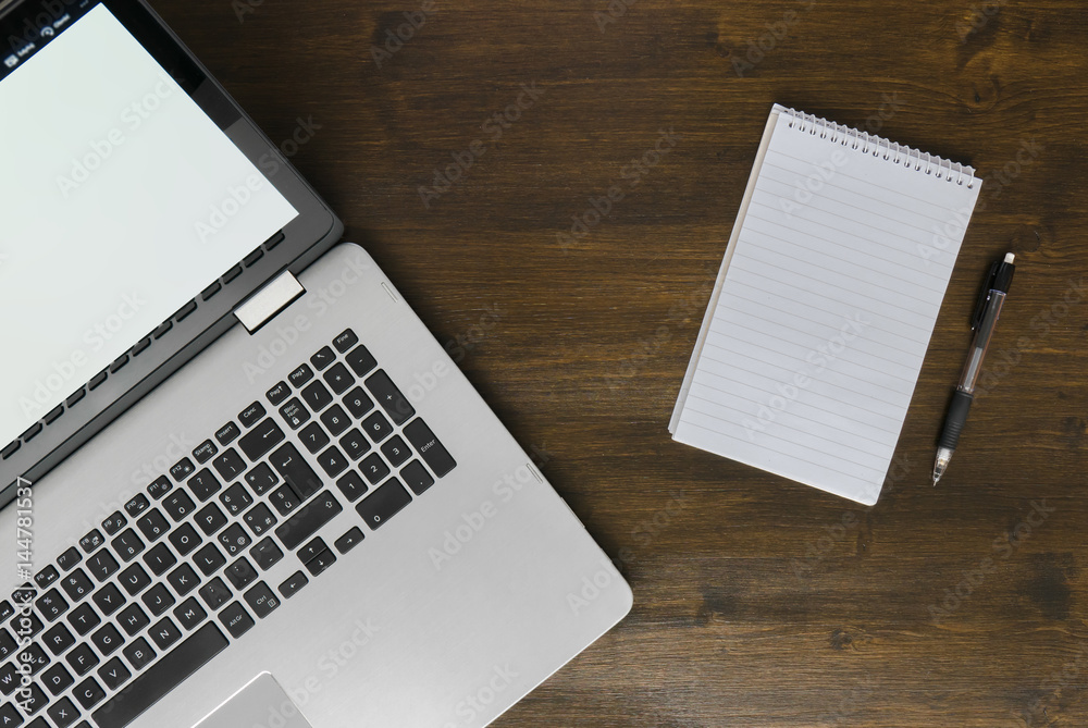 Top view of laptop and notepad on desk, dark brown wooden workspace concept Top view of laptop and notepad on desk, dark brown wooden workspace concept
