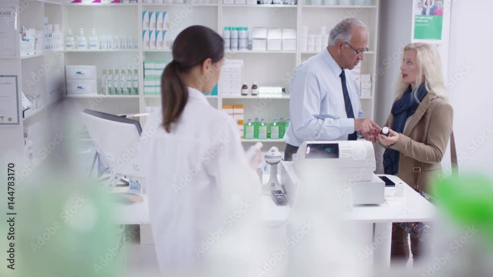 Team of staff working & serving customers in a chemist shop Team of staff working & serving customers in a chemist shop