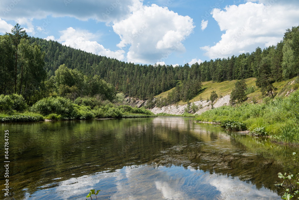 Mirror-like surface of river Belaya among mountains in summer day