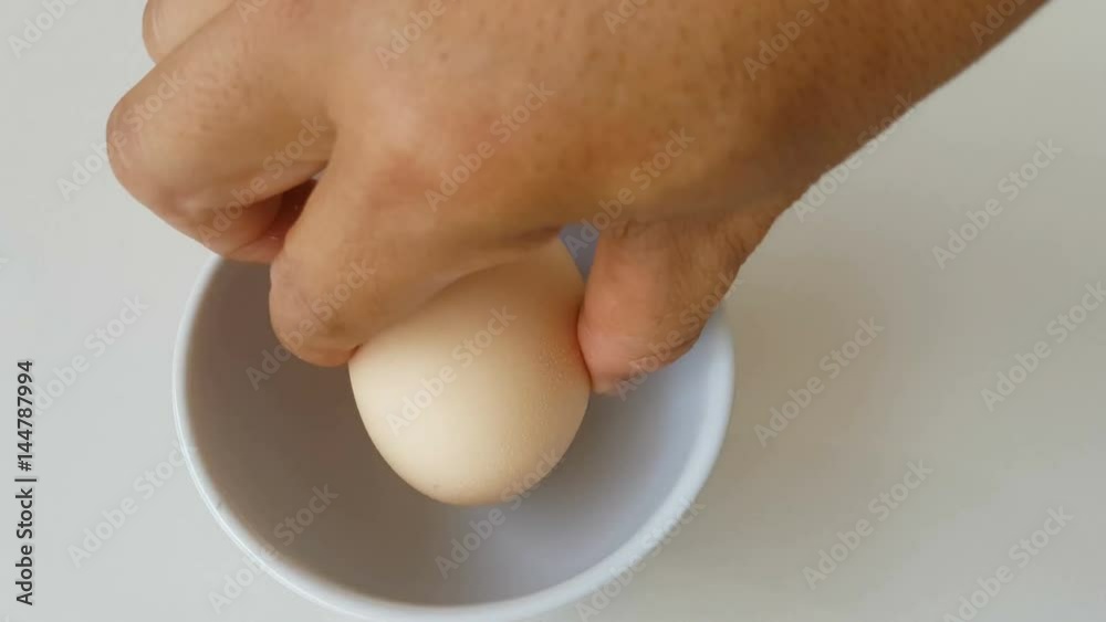 closeup hand cracking an egg with two yolks in a bowl