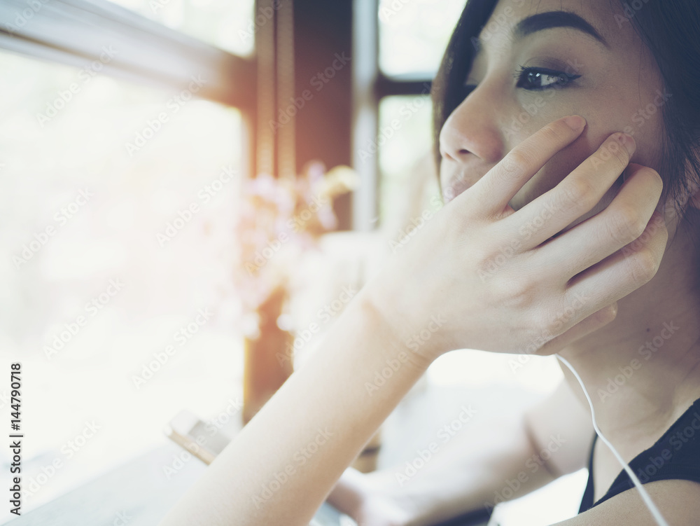 A beautiful Asian woman sitting on the coffee shop with smiley face and feeling happy A beautiful Asian woman sitting on the coffee shop with smiley face and feeling happy