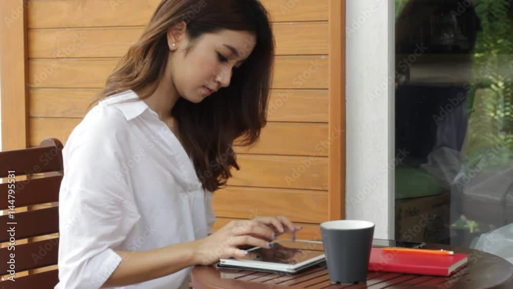Portrait of thai adult beautiful girl white shirt using her tablet.