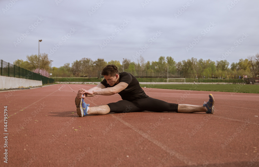 one young man, stretching leg, running tracks one young man, stretching leg, running tracks